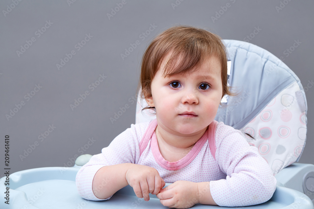 Adorable toddler girl is having fun while eating some fruits on greyish background Adorable toddler girl is having fun while eating some fruits on greyish background