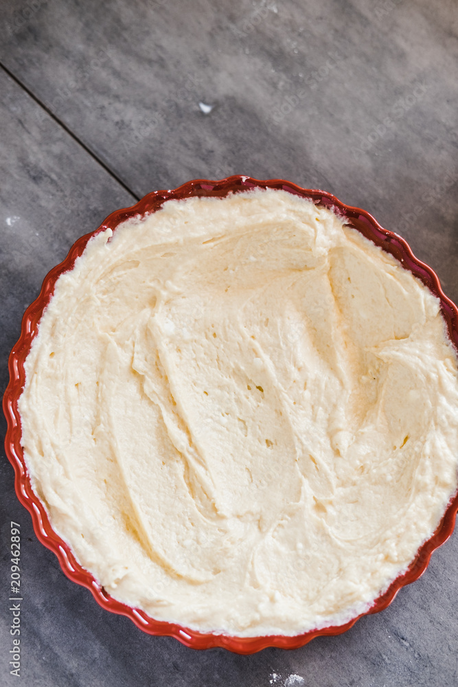 Butter in a red round ceramic tart baking pan. Making pie concept. Minimal dark food photography styling. Vertical, flat lay Butter in a red round ceramic tart baking pan. Making pie concept. Minimal dark food photography styling. Vertical, flat lay