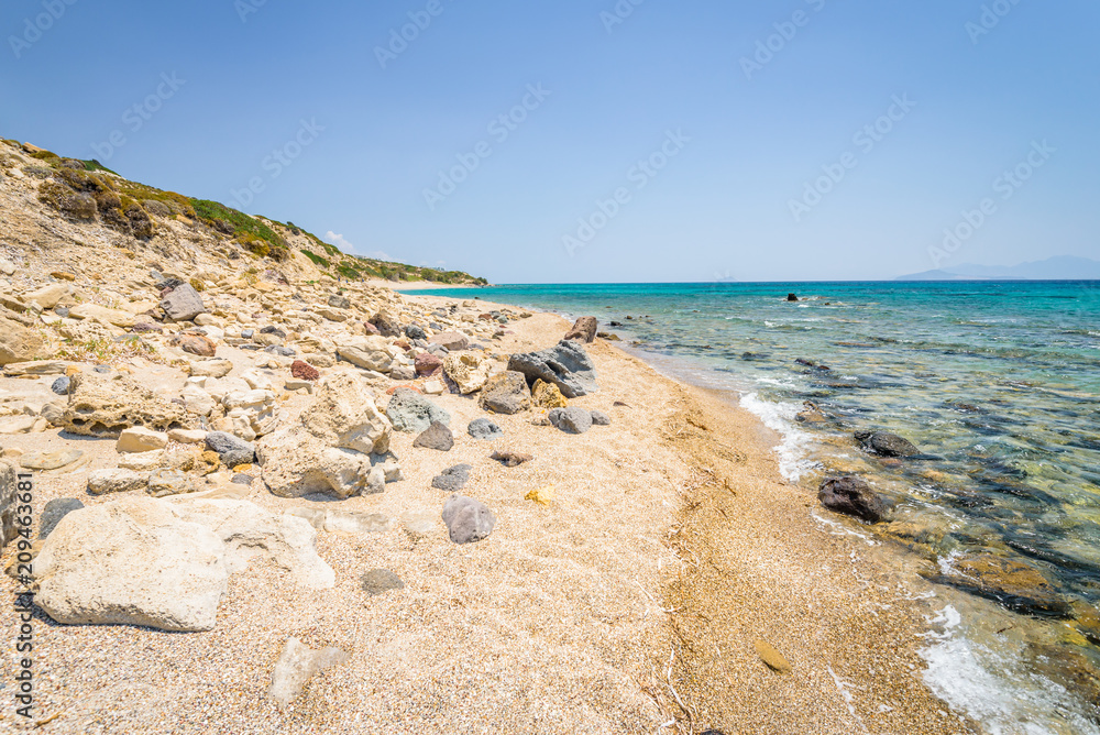 Beaches, Greece, Kos Island, Cap Helona: beautiful holiday setting on a secluded beach with umbrellas on the Greek Aegean Sea with turquoise waters and a picturesque bay and islands in the background Beaches, Greece, Kos Island, Cap Helona: beautiful holiday setting on a secluded beach with umbrellas on the Greek Aegean Sea with turquoise waters and a picturesque bay and islands in the background