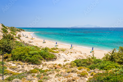 Beaches  Greece  Kos Island  Cap Helona  beautiful holiday setting on a secluded beach with umbrellas on the Greek Aegean Sea with turquoise waters and a picturesque bay and islands in the background