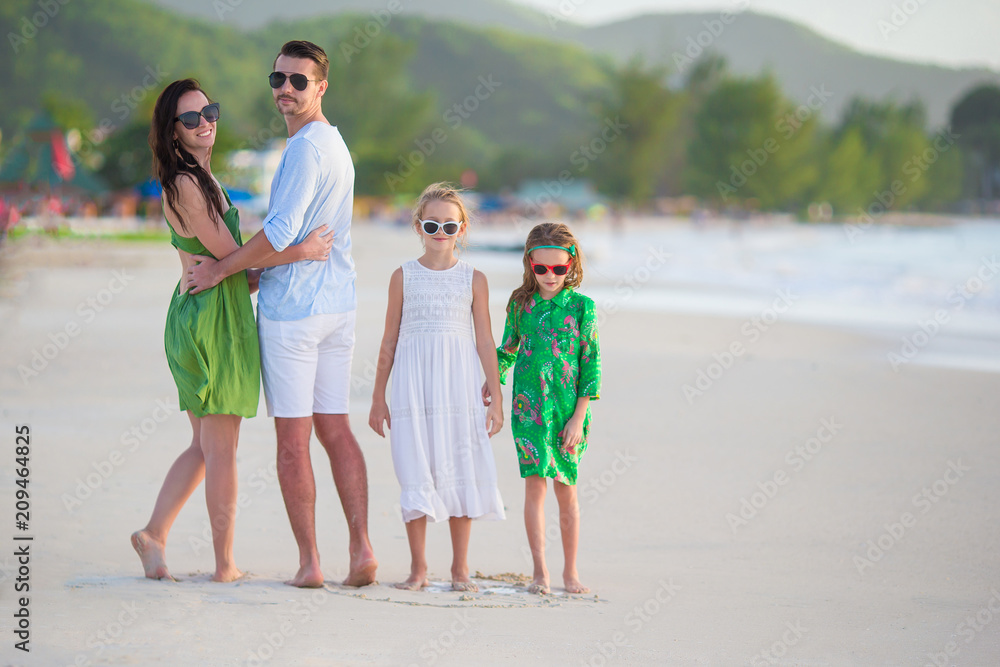 Family of four walking on white beach Family of four walking on white beach