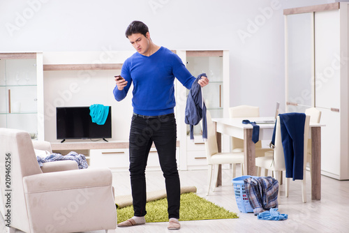 Young man collecting dirty clothing for laundry