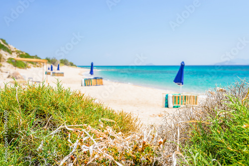 Beaches  Greece  Kos Island  Cap Helona  beautiful holiday setting on a secluded beach with umbrellas on the Greek Aegean Sea with turquoise waters and a picturesque bay and islands in the background