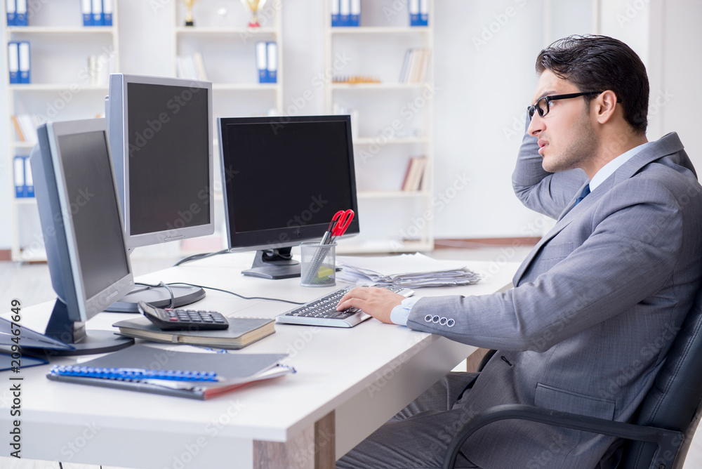 Businessman sitting in front of many screens