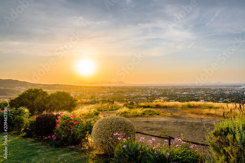 Kos Island, Town, Kalymnos, Greece - Warm sunset over the greek mediterranean sea near the turkish coast, viewed from the mountains of the island in a picturesque garden with many wildflowers