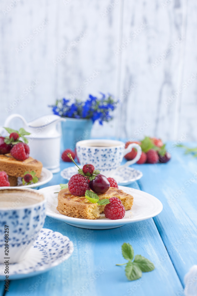 Small pies with berries, strawberries and cherries. Delicious sweet breakfast and fragrant coffee, on a blue wooden background. Flat lay, Copy space Small pies with berries, strawberries and cherries. Delicious sweet breakfast and fragrant coffee, on a blue wooden background. Flat lay, Copy space