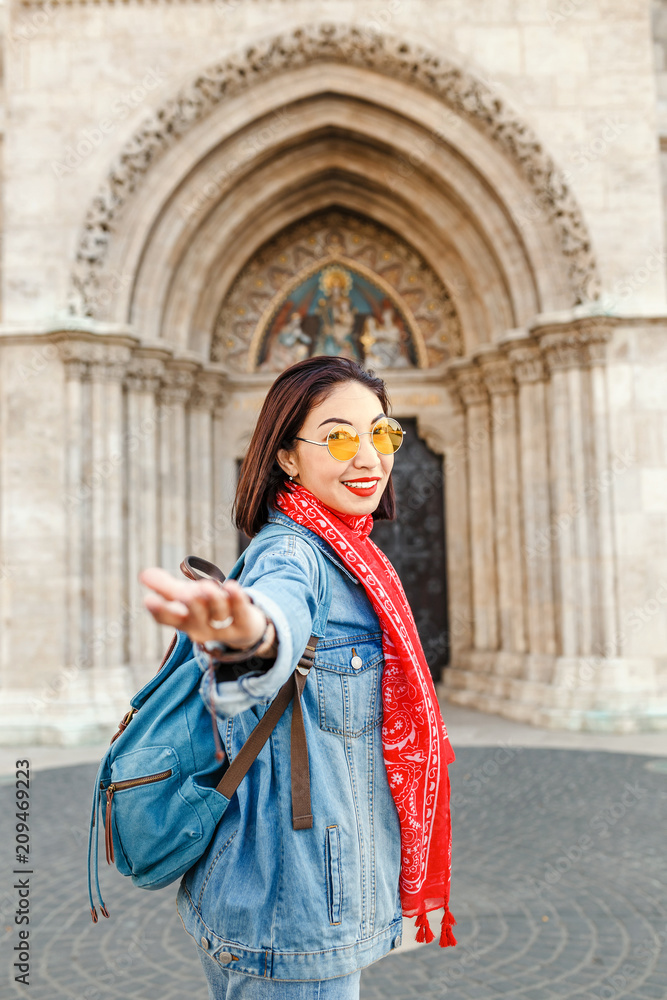 Follow me to Matthias church in Budapest. Mixed race woman traveler with backpack heading to tourist sights and destinations in Europe Follow me to Matthias church in Budapest. Mixed race woman traveler with backpack heading to tourist sights and destinations in Europe