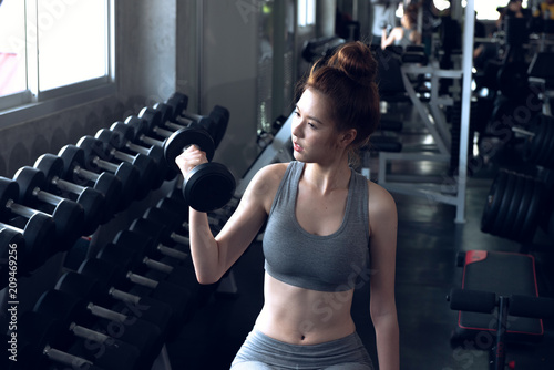 Attractive young sports woman lifting weights in the sport gym ,bodybuilding and loose weight concept.