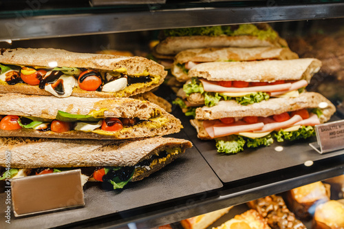 sandwiches stuffed with ham and tomato for sale in a bakery shop