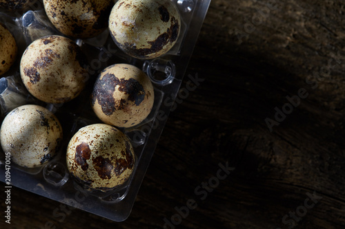 Spotted quail eggs arranged on the background of old wooden boards, with copy-space, selective focus. photo