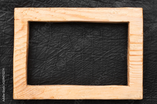 Beautiful wooden frame cut from a solid board, lies on a black leather.