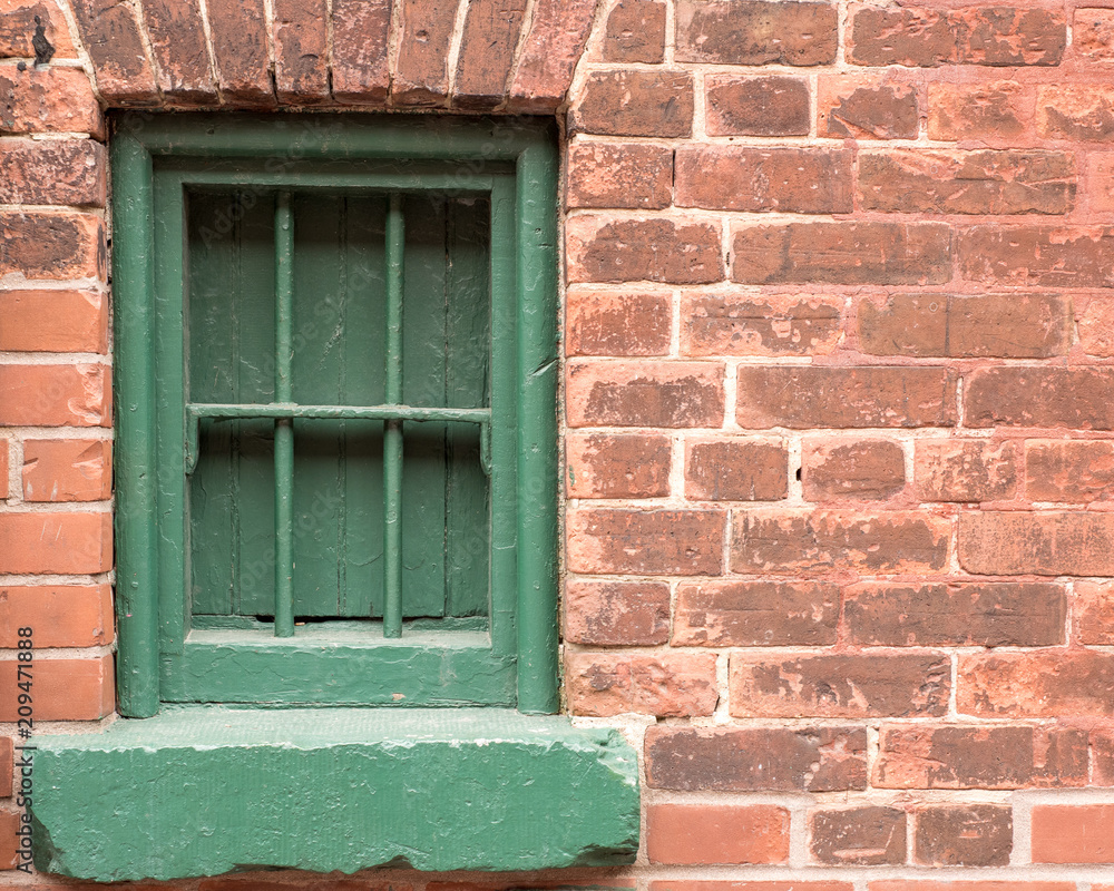 Green window with bars on a brick wall with vintage look ideal for business open closed sign