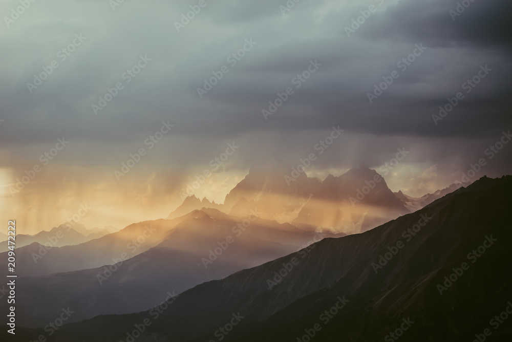 Mountains of Svaneti against the background of evening sky. The rays of setting sun illuminate snow-covered rocks of Georgia. Mountain tourism. Hike to the top.