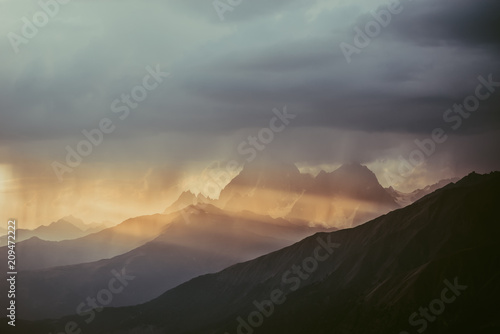 Mountains of Svaneti against the background of evening sky. The rays of setting sun illuminate snow-covered rocks of Georgia. Mountain tourism. Hike to the top. © KOSIM
