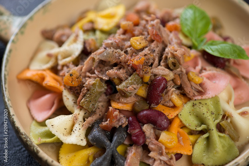 Closeup of farfalle pasta with tuna fillet, red beans and corn, selective focus, horizontal shot