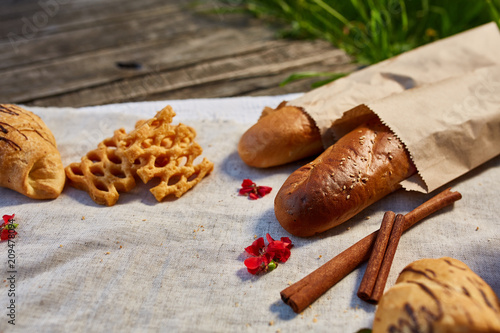 Picnic on a green lawn, pastries and vegetables on a homespun tablecloth, summer season, flat lay, selective focus