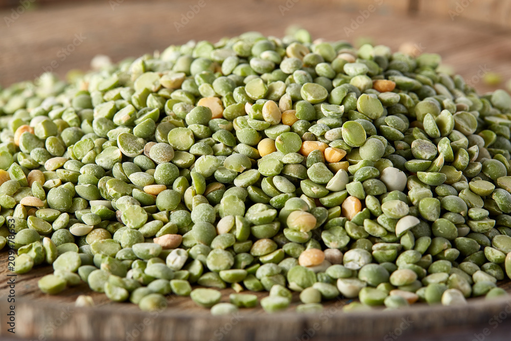 Pile of green peas on the top of wooden barrel, close-up, top view, selective focus. Pile of green peas on the top of wooden barrel, close-up, top view, selective focus.