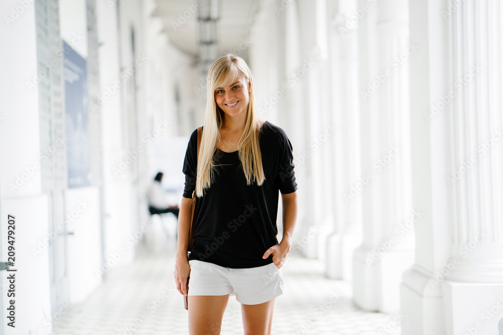 Portrait of a young and charming blonde woman with blue eyes. She is wearing a black shirt and white shorts. Portrait of a young and charming blonde woman with blue eyes. She is wearing a black shirt and white shorts.