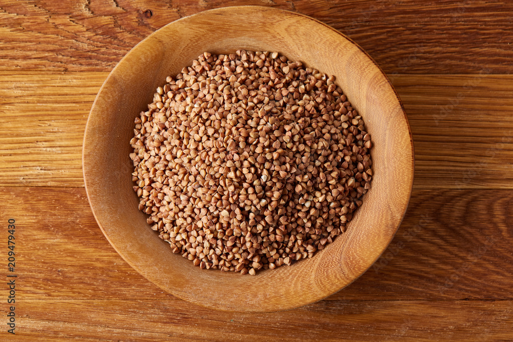 Bowl full of buckwheat grains on rustic wooden table, close-up, selective focus, shallow depth of field. Bowl full of buckwheat grains on rustic wooden table, close-up, selective focus, shallow depth of field.