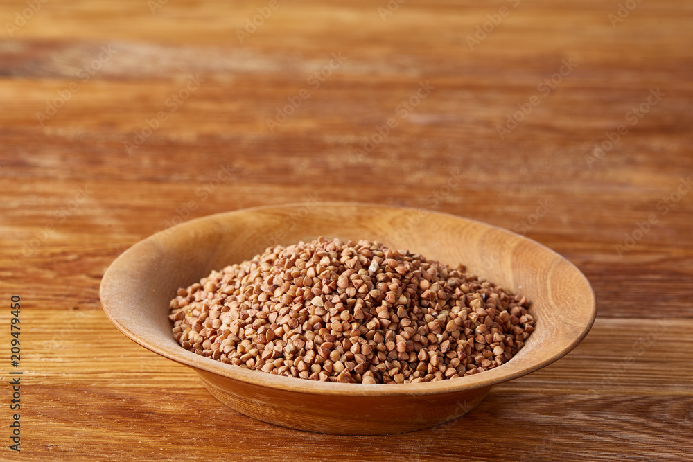 Bowl full of buckwheat grains on rustic wooden table, close-up, selective focus, shallow depth of field. Bowl full of buckwheat grains on rustic wooden table, close-up, selective focus, shallow depth of field.