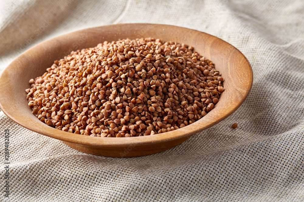 Bowl full of buckwheat grains on rustic wooden table, close-up, selective focus, shallow depth of field. Bowl full of buckwheat grains on rustic wooden table, close-up, selective focus, shallow depth of field.