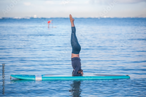 Obraz na plátne Sunny morning work out a pretty young woman in SUP Yoga practice head stand at A