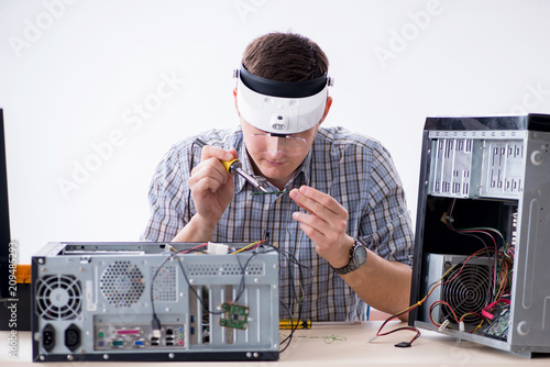 Young technician repairing computer in workshop