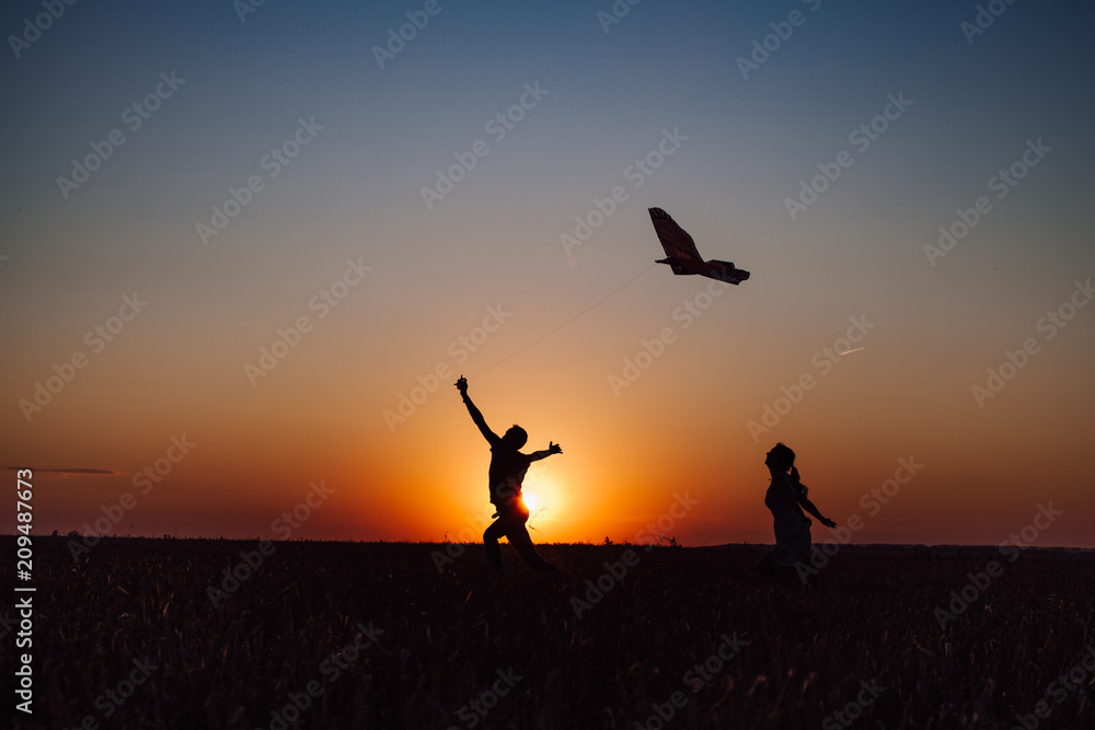 loving couple is running with kite at sunset