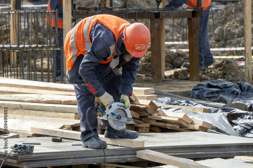 Khimki, Russia - June 14, 2018: Worker at the construction site sawing Khimki, Russia - June 14, 2018: Worker at the construction site sawing