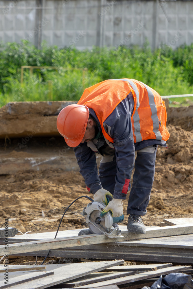 Khimki, Russia - June 14, 2018: Worker at the construction site sawing Khimki, Russia - June 14, 2018: Worker at the construction site sawing