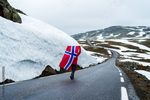 Girl with a Norwegian flag on a mountain road in Norway