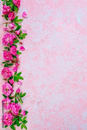 Border of pink roses on a pink old ructic concrete background  pastel  top view  copy space