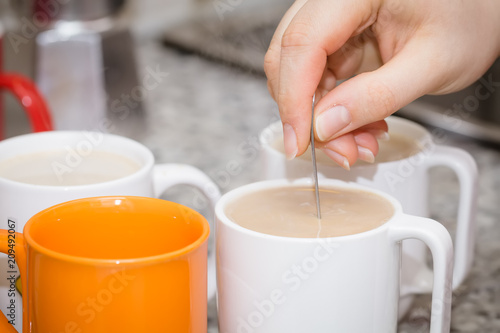 Mug coffee with milk and stir with a spoon