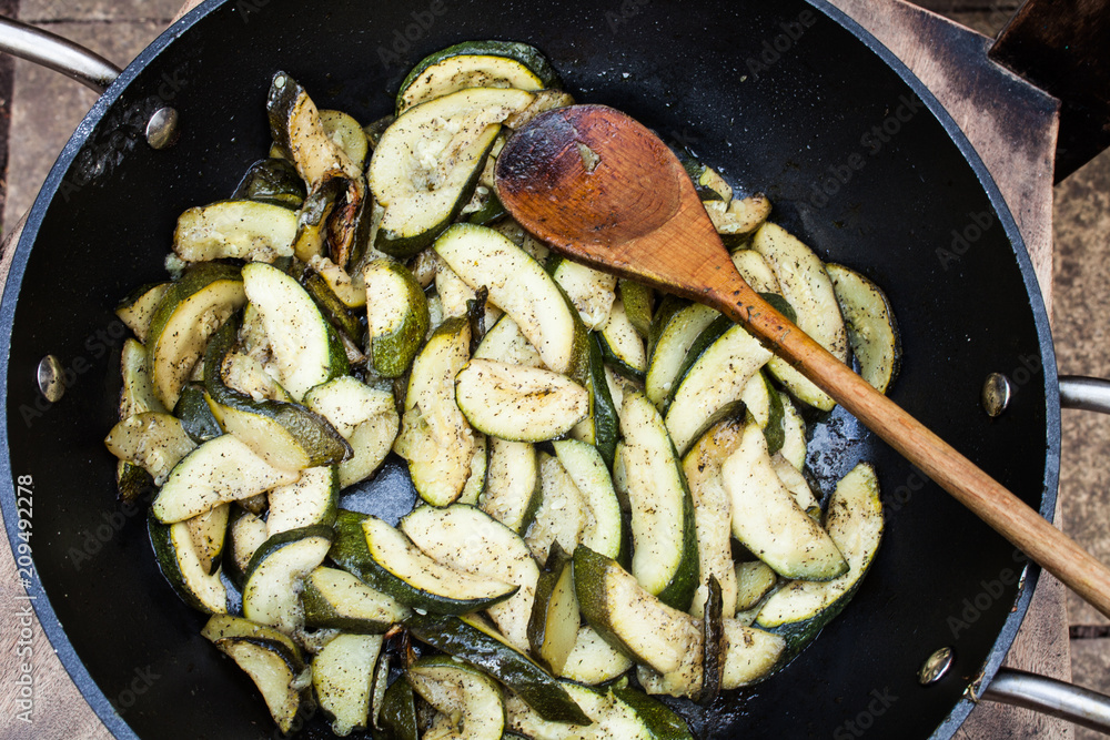 Preparation of zucchini in frying pan with hot oil. Delicious vegetables sliced and fried in oil. Vegetarian food fried in frying pan. Sliced courgette and prepared in hot oil. Preparation of zucchini in frying pan with hot oil. Delicious vegetables sliced and fried in oil. Vegetarian food fried in frying pan. Sliced courgette and prepared in hot oil.