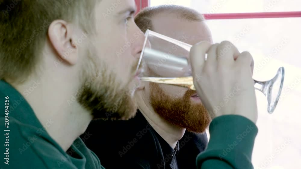 Close-up shot of two old friends drinking draft beer and talking in the pub. 4K Close-up shot of two old friends drinking draft beer and talking in the pub. 4K