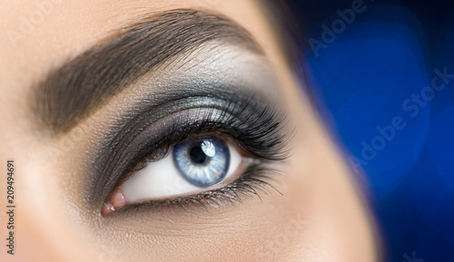 Fototapeta Naklejka Na Ścianę i Meble -  Woman blue eye with perfect makeup. Beautiful professional smokey eyes holiday make-up. Eyebrows shaping, eyes and eyelashes. Skin care