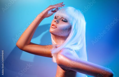 Fashion model girl in colorful bright sparkles and neon lights posing in studio, portrait of beautiful woman, trendy glowing make-up. White hair, colorful make up. Glitter vivid neon makeup