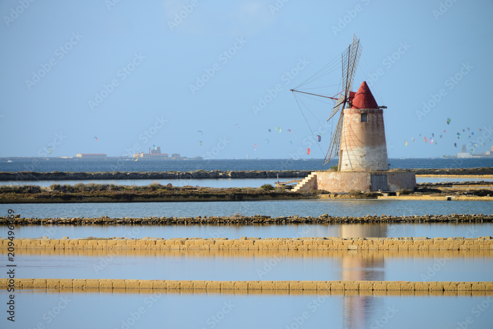 Traditional salt manufacturing windmill with kite surfer in the background, Saline di Trapani, Sicily, Italy