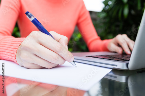 Businesswoman writing with pen on blank pice of paper.