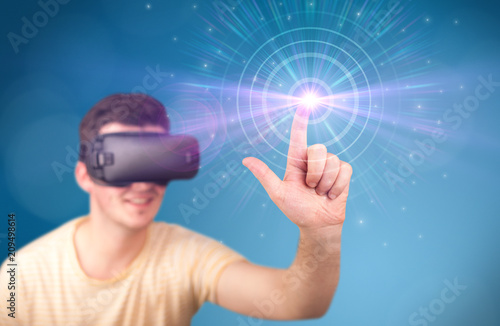 Young impressed man wearing virtual reality goggles with blue circles around his finger 