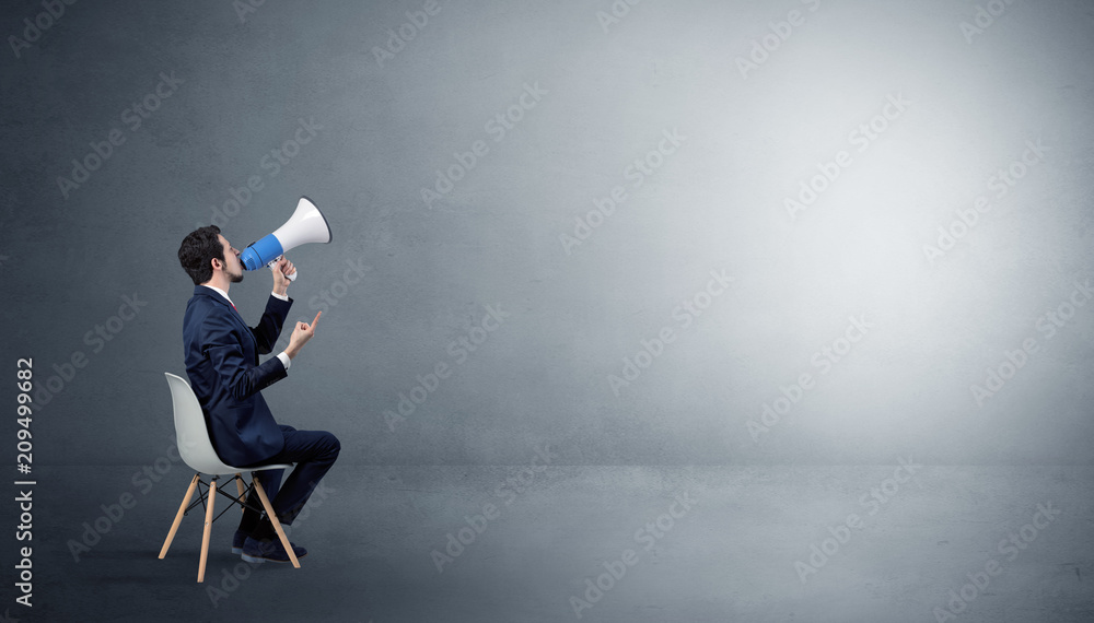 Businessman staying in an empty grey dark room with stuffs on his lap
Businessman staying in an empty grey dark room with stuffs on his lap