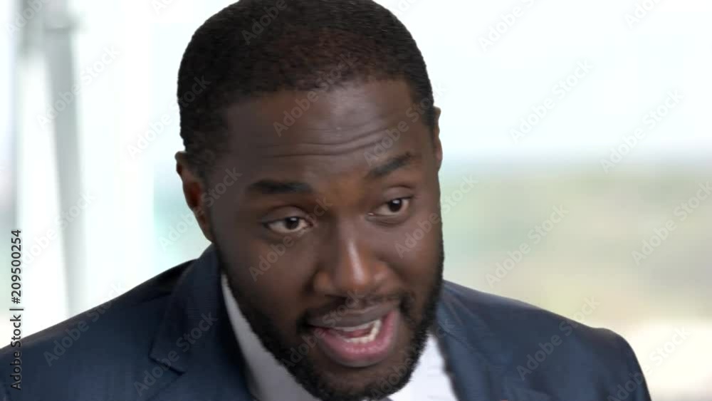 Face of afro-american businessman talking with microphone. Cheerful dark-skinned man in business suit speaking in microphone close up. Face of afro-american businessman talking with microphone. Cheerful dark-skinned man in business suit speaking in microphone close up.
