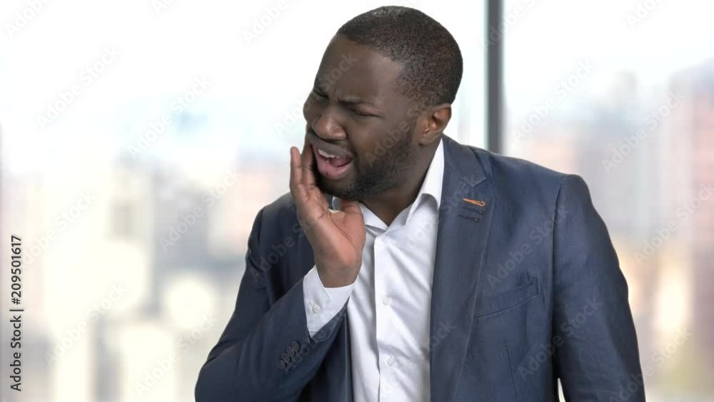 Man suffering from toothache. African-american businessman having terrible tooth pain on blurred background. Man suffering from toothache. African-american businessman having terrible tooth pain on blurred background.