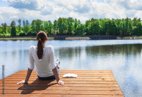 Young female sitting on edge of beautiful lake enjoying the view. 