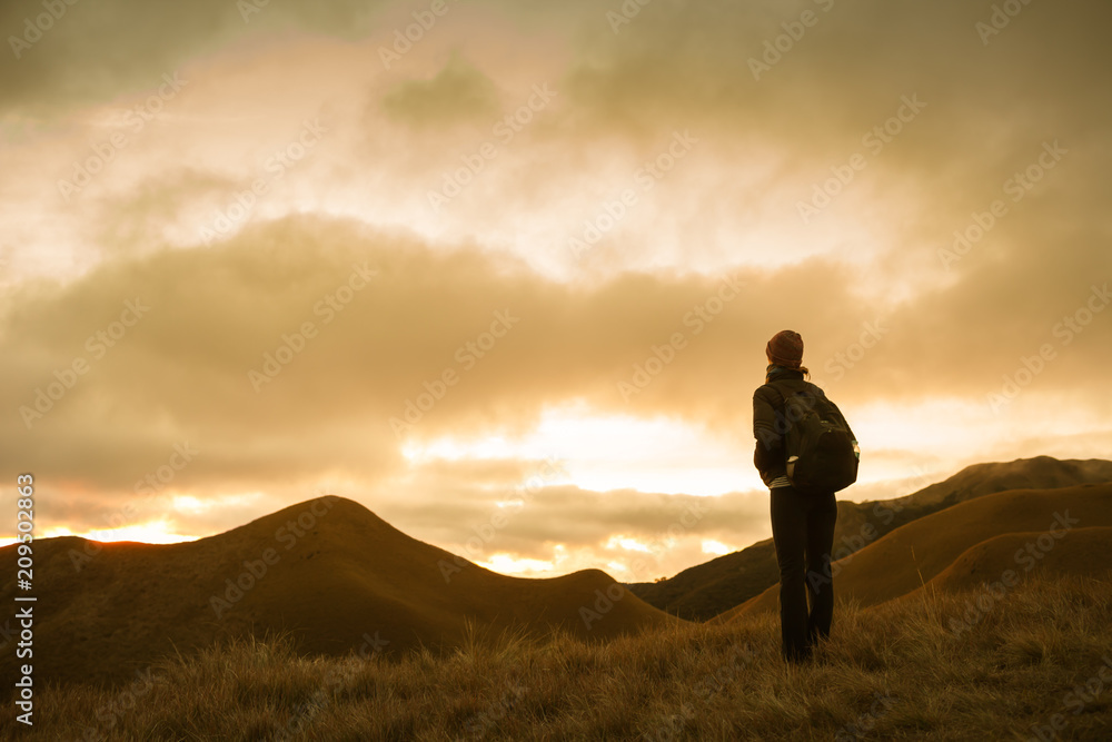 Female hiker stopping to enjoy the mountain sunset view.