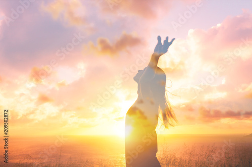 Happiness and joy. Young female feeling free in the sunset with arms up in air. Double exposure