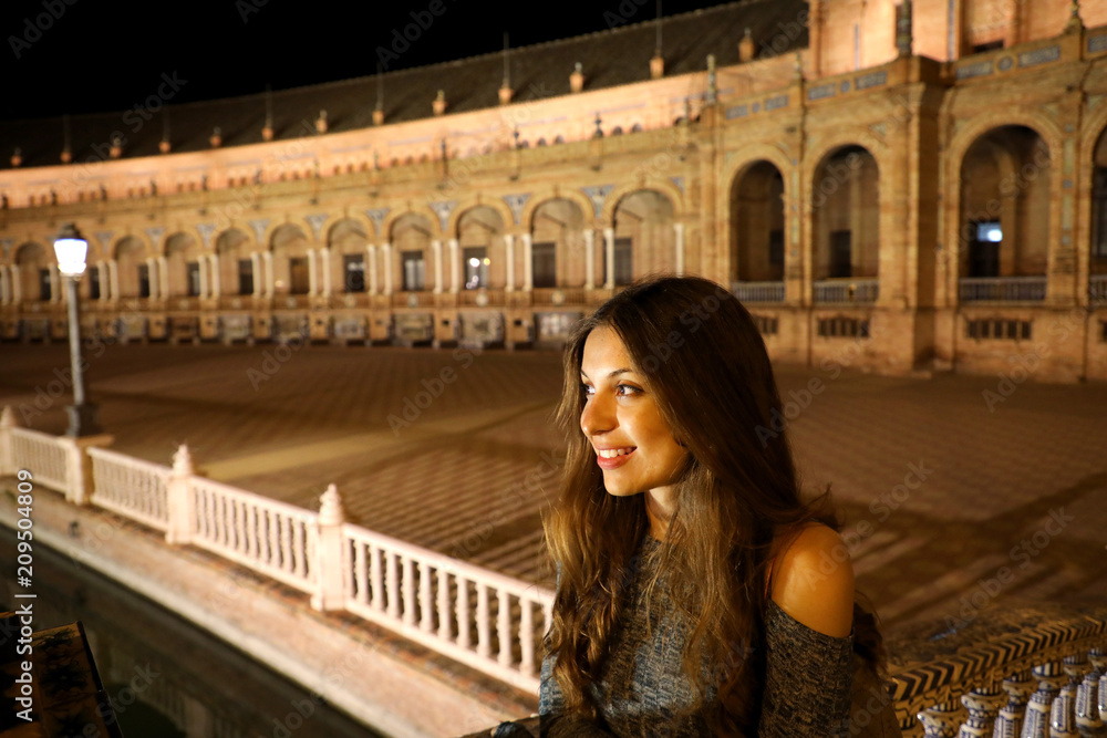 Night view of beautiful young woman in Plaza de Espana, Seville, Spain