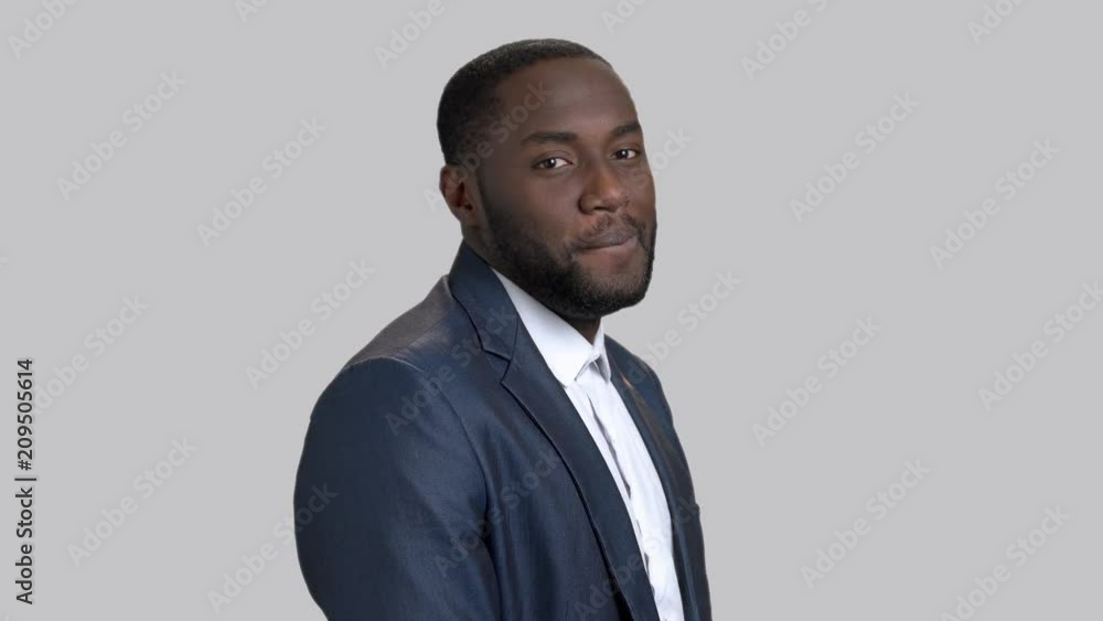 Black flirtatious businessman on grey background. Portrait of joyful dark-skinned macho-man. Invitation for a date gesture. Black flirtatious businessman on grey background. Portrait of joyful dark-skinned macho-man. Invitation for a date gesture.