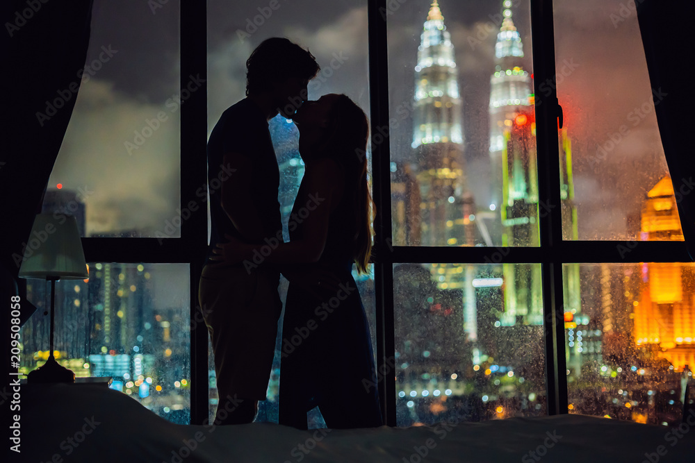 Silhouette of a loving couple against a window with a view of the night ...