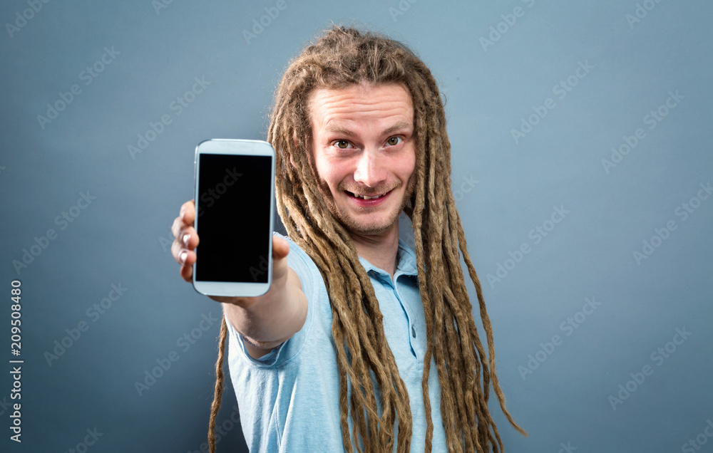 Young man holding out a cellphone in his hand